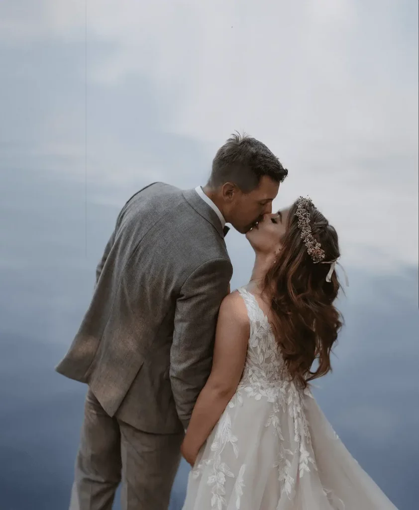 Hochzeitspaar küssen sich vor einem See