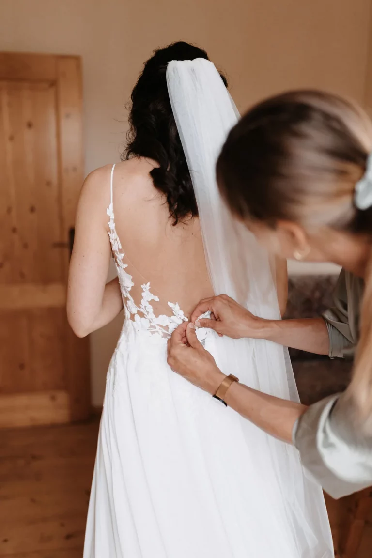 Braut bekommt Hilfe beim Anziehen ihres Brautkleides